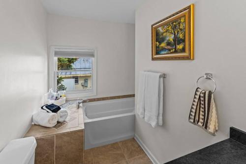 a white bathroom with a tub and a window at Sunshine Cottage in New Bern