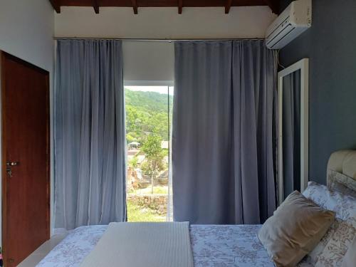 um quarto com uma cama e uma grande janela em Casa praia do Forte em Florianópolis