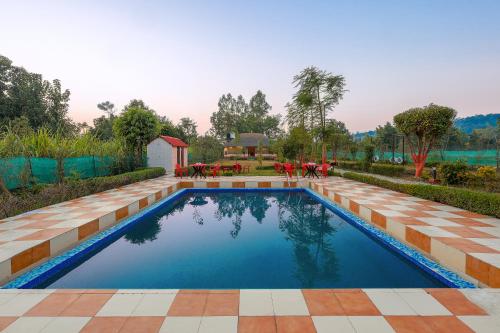 a swimming pool in a backyard with a tiled floor at Mud House by ChanchalRani in Rāmnagar