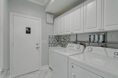una cocina blanca con armarios blancos y electrodomésticos blancos en Glamour House, en Wellington