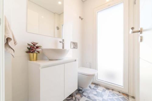 een witte badkamer met een wastafel en een toilet bij Villa Beija Flor in Charneca
