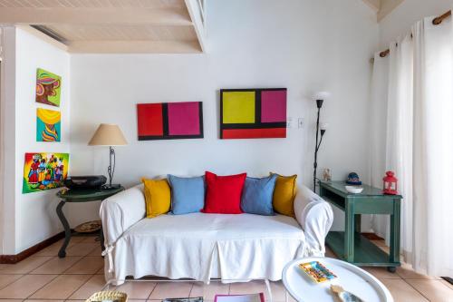a living room with a white couch with colorful pillows at Idyllic Beachfront Condo in Ocho Rios