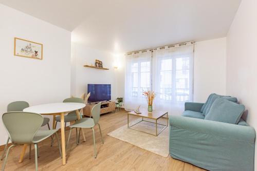 un salon avec une table et un canapé bleu dans l'établissement L'Emeraude by Plaza - Proche Disneyland Paris, à Chessy