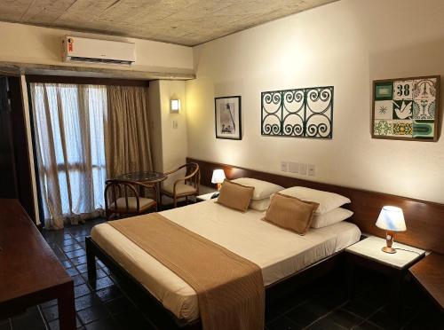 a hotel room with a large bed and a table at Hotel Catharina Paraguaçu in Salvador