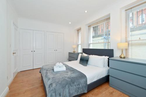 a bedroom with a bed and a dresser and windows at London Choice Apartments - Gloucester Road - Kensington in London