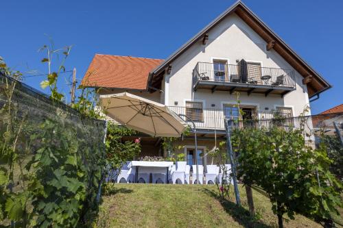 a white house with an umbrella and some vines at Winzerzimmer Scharl in Sankt Anna am Aigen