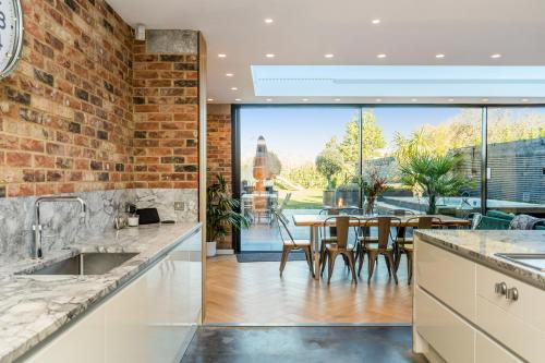 an open kitchen and dining room with a brick wall at Nutkin Barn - Contemporary home in West Sussex in Chichester