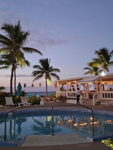 a pool at a resort with palm trees and the ocean at Sibonne Beach Hotel in Grace Bay