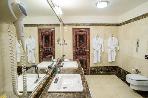 a bathroom with three sinks and white suits hanging on the wall at SK Royal Hotel Moscow in Moscow