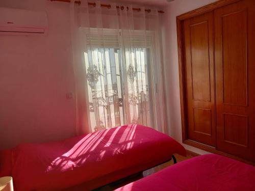 Cama roja en habitación con ventana en A room with a Sun view B&B, en Orihuela