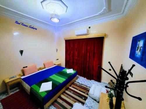 a bedroom with a bed and a red curtain at Riad Fennec Sahara in Zagora