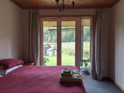 a bedroom with a bed and a large window at Ahaura Lodge & Waterwheel Farm Stay in Totara Flat