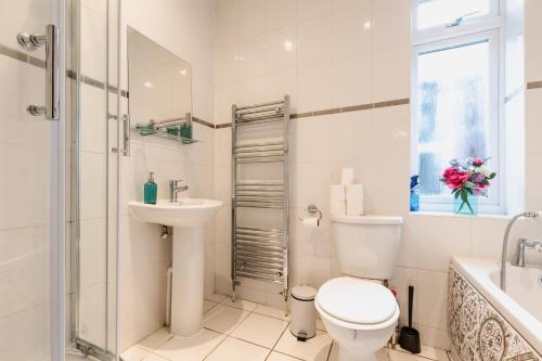 a white bathroom with a toilet and a sink at Accessible 3-bedroom bungalow with patio +driveway in Southampton