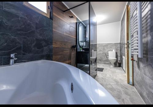 a white tub in a bathroom with a toilet at Kovacevic Weekend House in Lokva