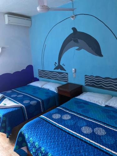 2 camas en una habitación con un delfín en la pared en Hotel Lu'um en Tecolutla