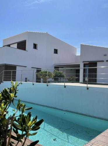 une maison avec une piscine en face d'un bâtiment dans l'établissement Villa d'Es Bot, à Cala Morell