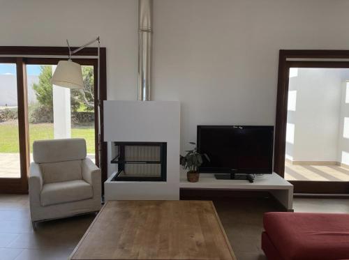 a living room with a television and a chair at Villa d'Es Bot in Cala Morell