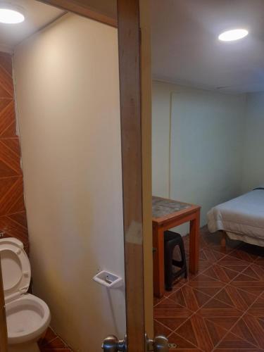 a bathroom with a toilet and a bed in a room at hostal consulado in Caldera