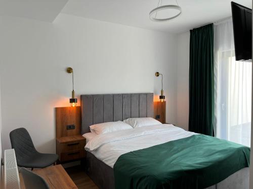 a bedroom with a large bed and a chair at Pensiunea Cascada in Borşa