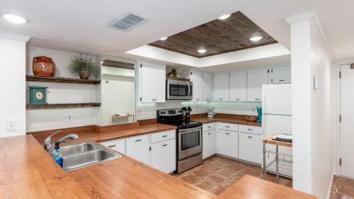 a kitchen with white cabinets and a wooden counter top at Oceanfront spectacular views with direct beach and pool access! in Ormond Beach