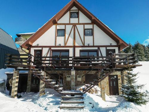 a house in the snow with a staircase in front at Alpine Retreat Čupino Sokače in Kopaonik