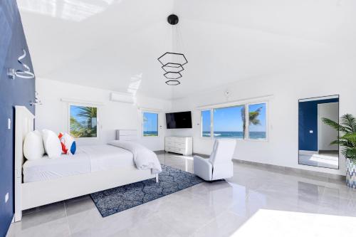 a white bedroom with a bed and a tv at Lovely 4-Bed Villa in Anguilla in Long Path