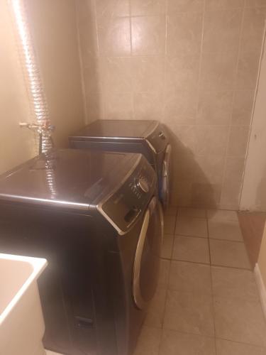 a small bathroom with a black washer and dryer at One bedroom basement suite with private living room and laundry. in Brampton