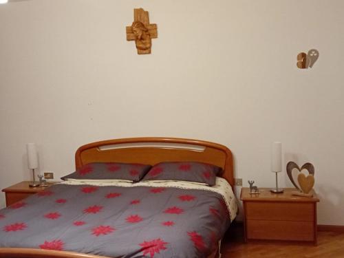 1 dormitorio con 1 cama con una cruz en la pared en la casa del zio Bepi, en Bedollo