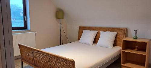 una piccola camera da letto con un letto con lenzuola e cuscini bianchi di Tranquility - Your home Away a Grez-Doiceau