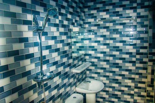 a blue and white tiled bathroom with a toilet and a sink at Résidence Roma in Cotonou