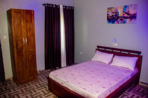 a bedroom with a bed and a wooden cabinet at Résidence Roma in Cotonou