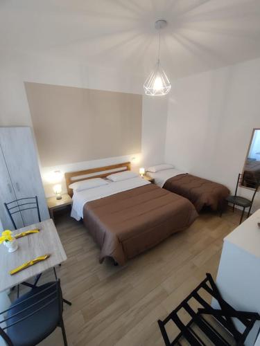 a bedroom with two beds and a table and chairs at B&B Vento Aureo Rooms in Milazzo