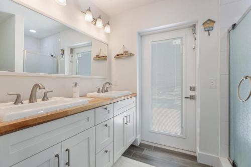 a white bathroom with two sinks and a shower at Seagrape Cottage in Bradenton Beach