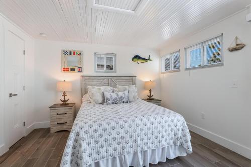 a white bedroom with a bed and two lamps at Seagrape Cottage in Bradenton Beach