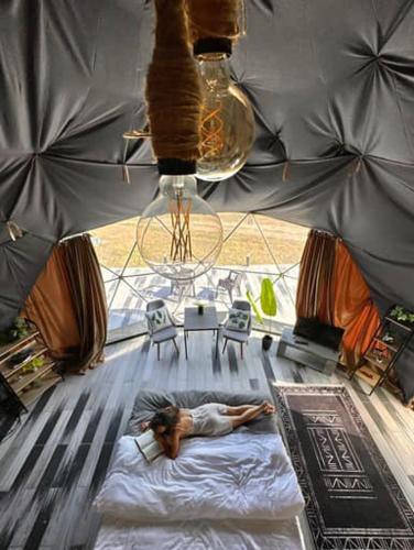 a woman laying on a bed in the middle of a room at Bolnisio Resort in Bolnisi