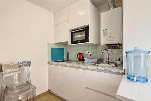une cuisine avec des placards blancs et un comptoir dans l'établissement Spacieux studio à 150m de la plage 2 terrasses, à Antibes
