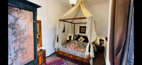 um quarto com uma cama de dossel num quarto em Dar Najat em Marraquexe