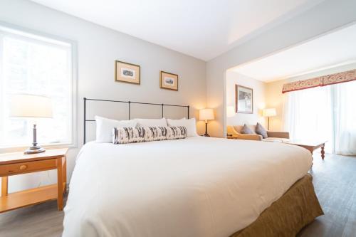 ein Schlafzimmer mit einem großen weißen Bett und einem Fenster in der Unterkunft Horseshoe Valley Suites - The Pine in Shanty Bay