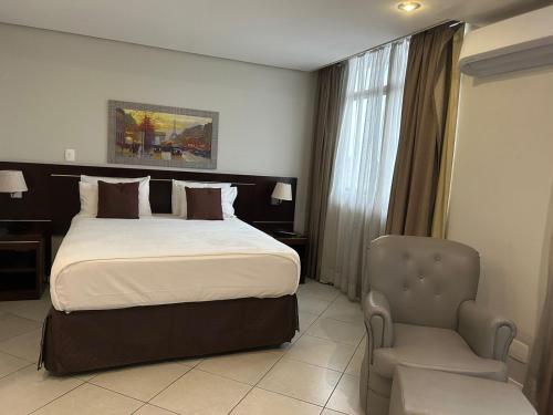um quarto de hotel com uma cama e uma cadeira em Millenium Hotel Flat em Manaus