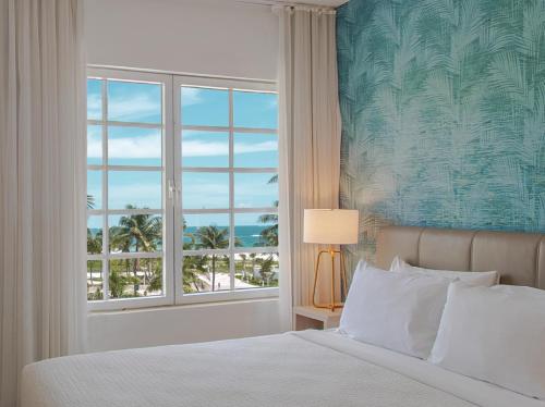 a bedroom with a bed and a window with a view of the ocean at Bentley Hotel South Beach in Miami Beach
