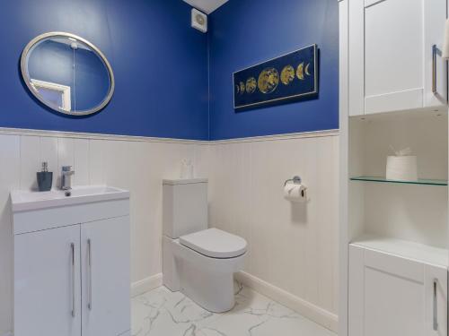 a bathroom with a white toilet and a blue wall at 4 bed in Worthing 83354 in Ferring