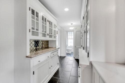a white kitchen with white cabinets and a tile floor at Bayshore Charmer in Tampa