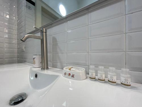 ein weißes Waschbecken mit einem Wasserhahn und einigen Flaschen in der Unterkunft BG Central Royal Suite con parcheggio - Vista Città Alta in Bergamo