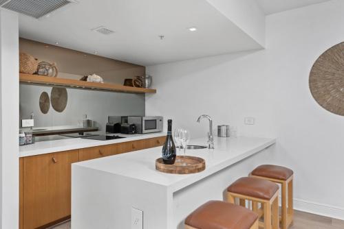 a kitchen with a white counter and stools in it at Bentley Hotel South Beach in Miami Beach