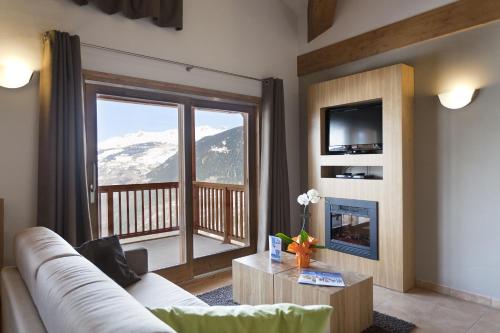 a living room with a couch and a view of a mountain at Résidence Club mmv L'Étoile des Cimes **** in Sainte-Foy-Tarentaise