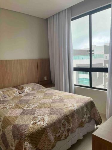 a bedroom with a bed and a large window at Flat espaçoso e estiloso na Praia do Bessa a uma quadra do mar! in João Pessoa