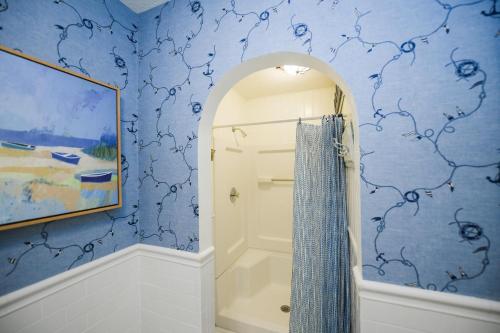 a bathroom with a shower and blue wallpaper at Buttonwood Cottage in Anna Maria