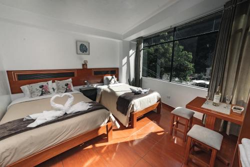 um quarto com 2 camas e uma janela em Escobedo’s Inn Machupicchu em Machu Picchu