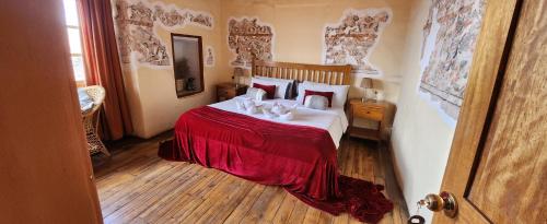 um quarto com uma cama com um cobertor vermelho em Loki Cusco em Cusco