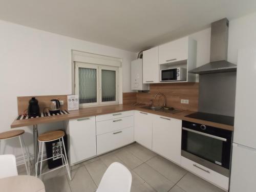 uma cozinha com armários brancos e electrodomésticos brancos em Chez François: appartement 3 chambres 4 personnes em Saint-Avold